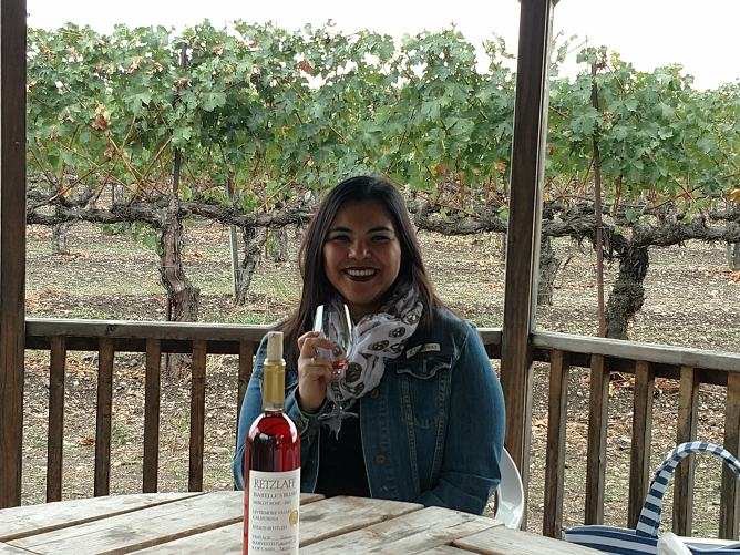 Moni holding up a wine glass, at a vineyard in Livermore. 